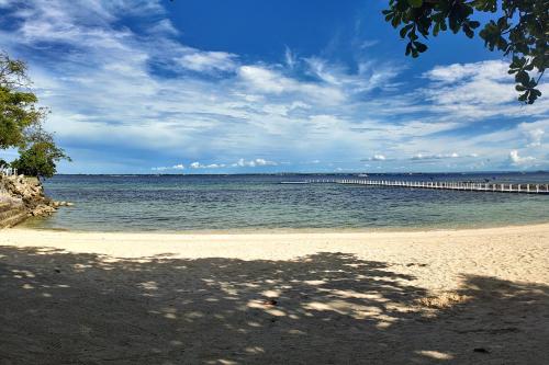 a sandy beach with a pier in the water at Dominiks Comfort and silent Studio Tambuli Balcony Pool Mactan Ocean View High Floor in Lapu Lapu City