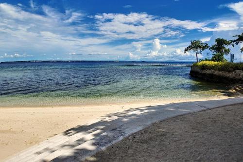 a view of the ocean from a sandy beach at Dominiks Comfort and silent Studio Tambuli Balcony Pool Mactan Ocean View High Floor in Lapu Lapu City