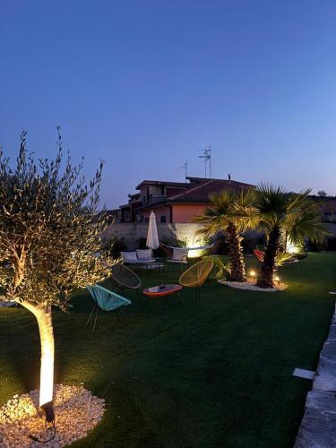 a garden with chairs and tables and palm trees at night at Sciara Casa Vacanze in Pedara
