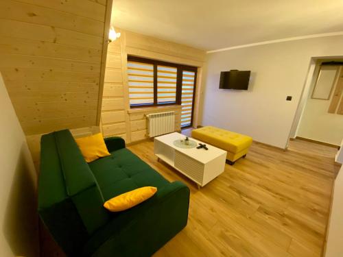 a living room with a green couch and a table at Apartament Chowańcówka z widokiem na góry typu studio obok stoków narciarskich i blisko basenów termalnych in Bukowina Tatrzańska