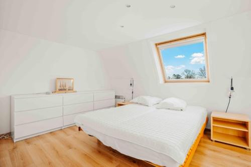 a white bedroom with a bed and a window at Vakantiewoning 'Carpe diem' te Oostduinkerke in Oostduinkerke