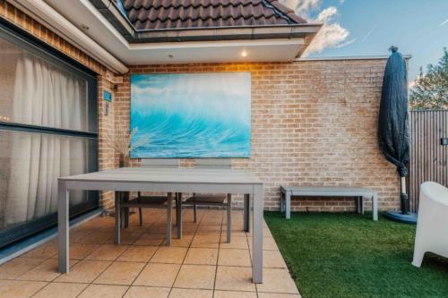 a table and benches on a patio with a brick wall at Vakantiewoning 'Carpe diem' te Oostduinkerke in Oostduinkerke