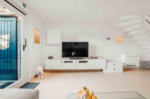a white living room with a flat screen tv at Vakantiewoning 'Carpe diem' te Oostduinkerke in Oostduinkerke
