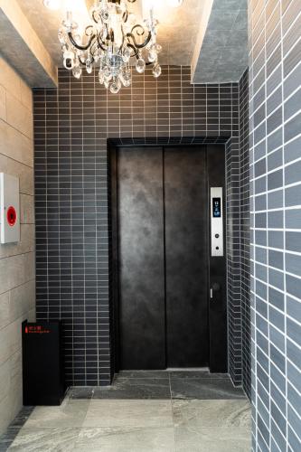 a black door in a building with a chandelier at KINSHICHO Tokyo Holiday Hotel in Tokyo