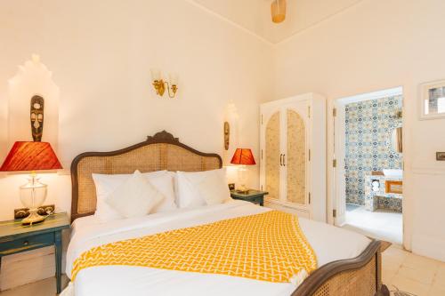 a bedroom with a bed and two lamps and a window at ELIVAAS Maison 10 - Luxe 4 BHK Villa With Pvt Pool, Garden & Portuguese Charm in Siolim