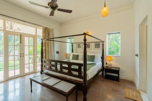 a bedroom with a canopy bed and a fan at ELIVAAS Maison 10 - Luxe 4 BHK Villa With Pvt Pool, Garden & Portuguese Charm in Siolim