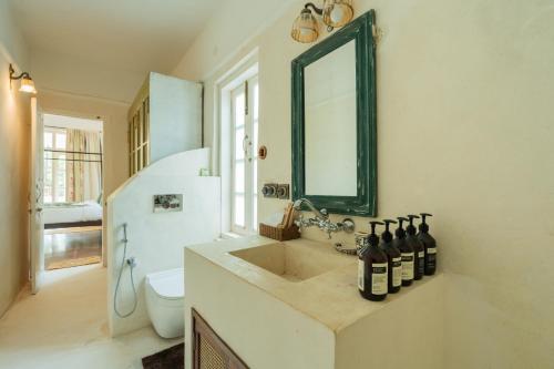 a bathroom with a sink with bottles of wine on it at ELIVAAS Maison 10 - Luxe 4 BHK Villa With Pvt Pool, Garden & Portuguese Charm in Siolim