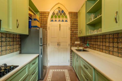 a kitchen with green cabinets and a white door at ELIVAAS Maison 10 - Luxe 4 BHK Villa With Pvt Pool, Garden & Portuguese Charm in Siolim