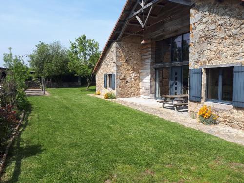 une maison avec une cour herbeuse à côté d'un bâtiment dans l'établissement Grange rénovée, à Bressuire