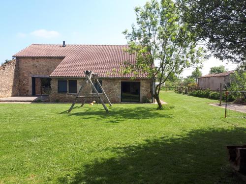 une cour avec une balançoire située en face d'une maison dans l'établissement Grange rénovée, à Bressuire