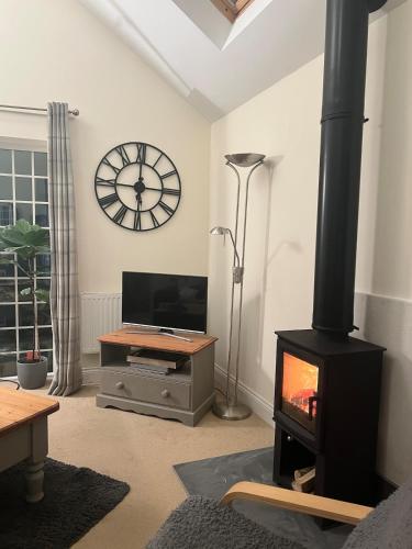 a living room with a wood stove and a clock at Ashbourne Cottage in Ringwood