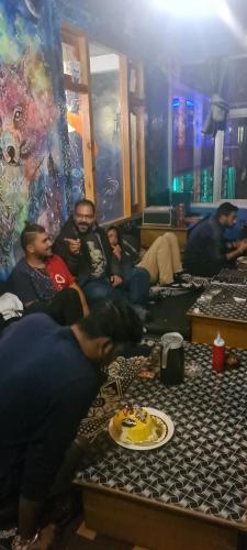 a group of people sitting in a room with a cake at Formosa cafe & hostel in Kasol