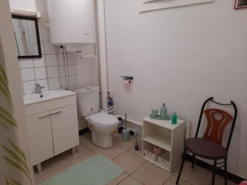 La salle de bains est pourvue de toilettes, d'un lavabo et d'une chaise. dans l'établissement Aux portes de nancy , studio avec parking gratuit, à Frouard