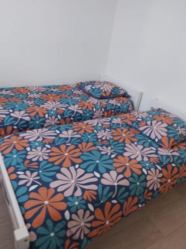 un lit avec un couvre-lit fleuri coloré dessus dans l'établissement Les Baleinières Les Sables d'Olonne La Chaume, à Les Sables-dʼOlonne