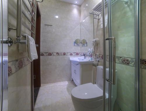a bathroom with a shower and a toilet and a sink at Grand Voyage Hotel in Almaty