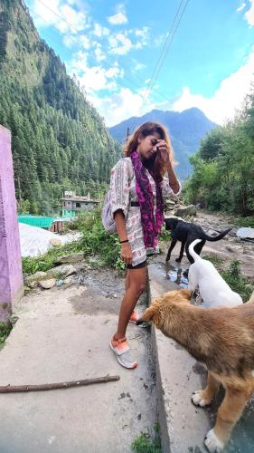 a young girl talking on a cell phone with two dogs at Formosa cafe & hostel in Kasol
