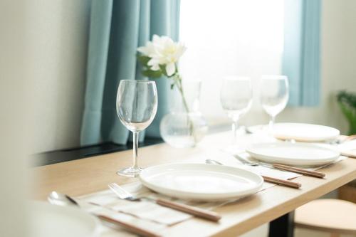 a table with plates and glasses and a vase with a flower at KINSHICHO Tokyo Holiday Hotel in Tokyo