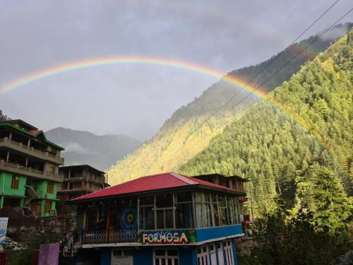 a rainbow over a building with a mountain at Formosa cafe & hostel in Kasol