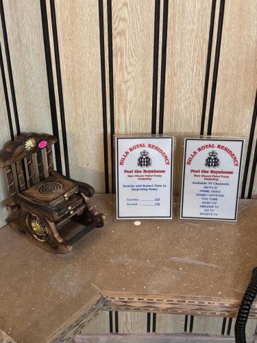 three signs on top of a table with a chair at Hills Royal Residency in Jālāpahār
