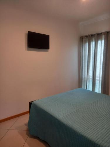 a bedroom with a bed and a television on the wall at Vilas Horizonte in Porto Santo