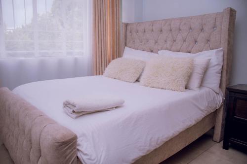 a bed with white sheets and pillows on it at Bellissima Homes in Kericho