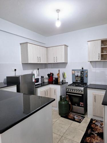 a kitchen with white cabinets and a black counter top at Bellissima Homes in Kericho