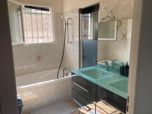 La salle de bains est pourvue d'un lavabo bleu et d'une baignoire. dans l'établissement Villa 13 personnes avec piscine à débordement, à Rocbaron