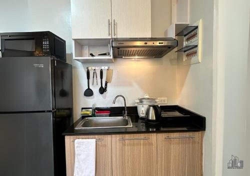 a small kitchen with a sink and a refrigerator at Palawan Luxury Stay with Balcony, Free Gym & Pool - B1 5Topaz in Puerto Princesa City