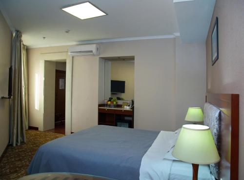 a hotel room with a bed and a lamp at Grand Voyage Hotel in Almaty