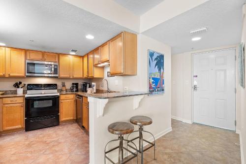 a kitchen with wooden cabinets and two bar stools at Perdido Towers West 906 in Perdido Key