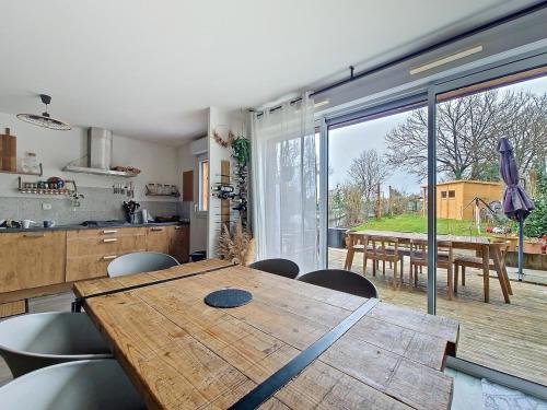 une cuisine et une salle à manger avec une table en bois et une grande fenêtre dans l'établissement Maison avec jacuzzi, à Saint-Erblon