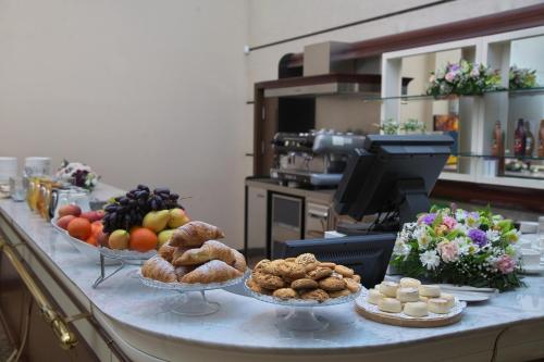 a buffet with bowls of fruit and pastries on a counter at Grand Voyage Hotel in Almaty