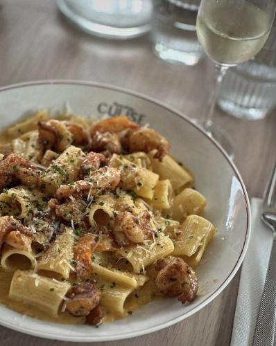 a plate of pasta with shrimp and a glass of wine at Privyrooms GORAKHPUR in Gorakhpur
