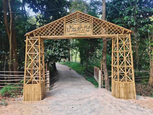 a wooden archway in the middle of a dirt road at Ban Kham Kee Homestay in Chiang Mai