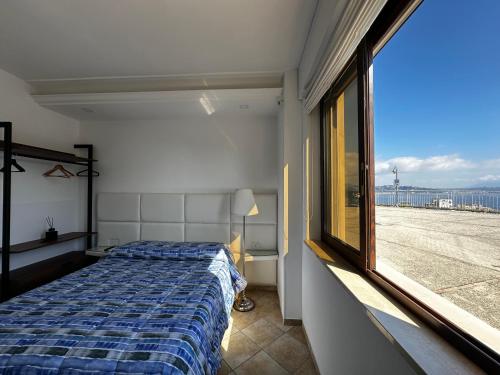 a bedroom with a bed and a large window at Re Vincy - Affittacamere in Bacoli