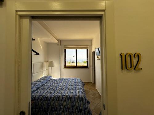 a hotel room with a bed and a window at Re Vincy - Affittacamere in Bacoli