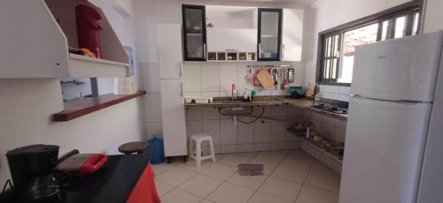 a kitchen with a white refrigerator and a white tile floor at Casa para relaxar a 600 M da Praia do Paí Vitório in Búzios