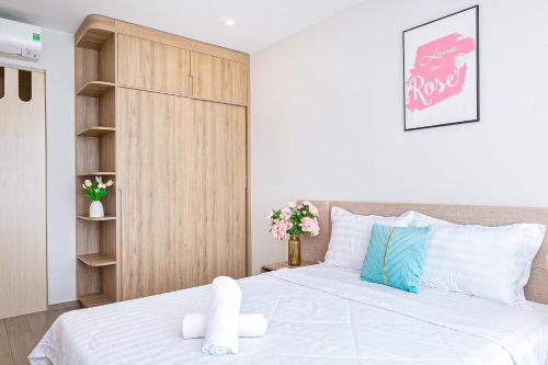 a bedroom with a white bed and a wooden closet at Cloud Nine The Song Vung Tau Homestay in Vung Tau
