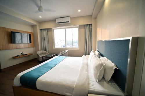 a hotel room with a large bed and a window at Hotel Prag Continental in Guwahati