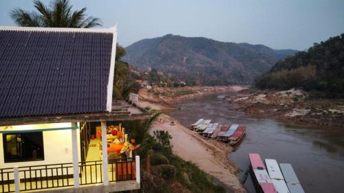 een gebouw naast een rivier met boten erop bij INN RIVERSIDE HOSTEL Pb in Pakbeng