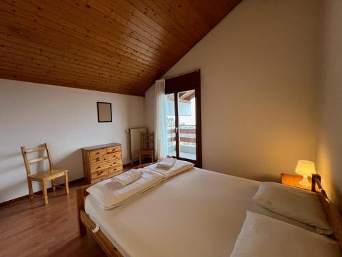 a bedroom with a bed and a chair and a window at Appartement pour 8 terrasse et Parking in Vionnaz