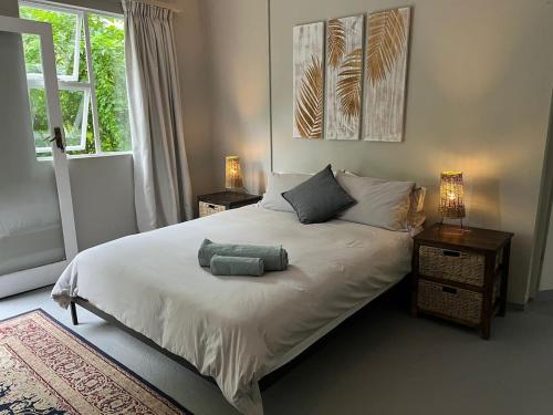 a bedroom with a white bed with two lamps and a window at Mngazana Hideaway in Port St Johns