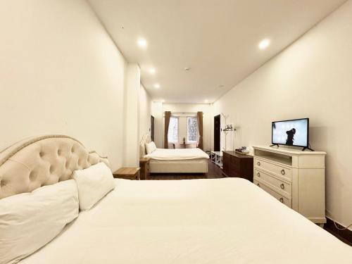 a bedroom with a large white bed and a television at TTR Joy Apart' Hotel in Da Lat