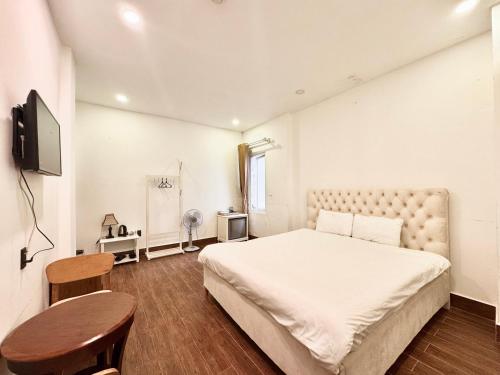 a bedroom with a large white bed and a table at TTR Joy Apart' Hotel in Da Lat
