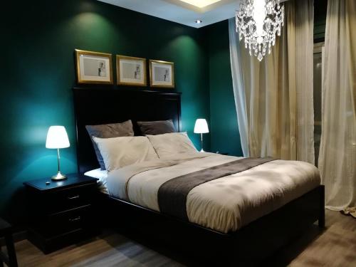 une chambre avec un lit aux murs verts et un lustre dans l'établissement Montana Residence, à Amman