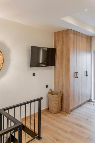 a living room with a staircase and a tv on the wall at Casa Myrtēssa in Myrtos