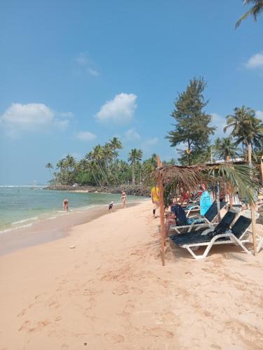 a group of chairs on a beach with the ocean at Crystal Wave Holiday Resort Polhena in Matara