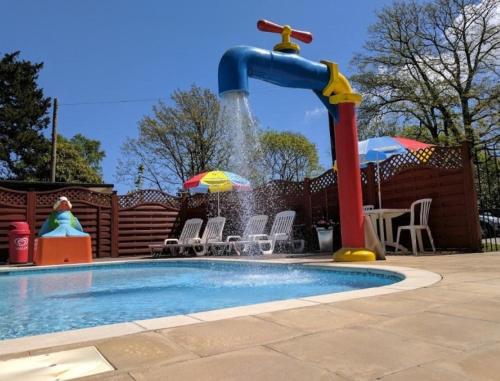 a swimming pool with a water fountain at Woodland Retreat Entire Holiday Home in Hastings in Hastings