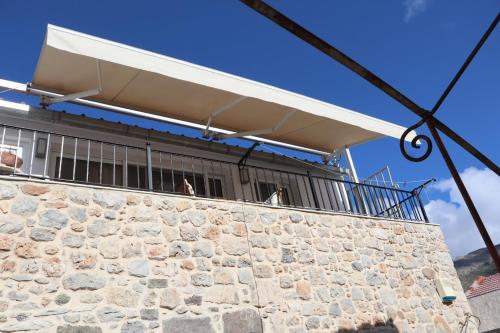 a building with a white balcony on top of a stone wall at FOTEINI RESIDENCE in Kalymnos