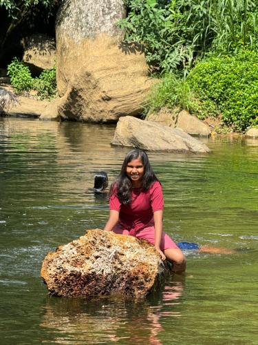 a woman sitting on a rock in the water at The Cave in Yatiyantota